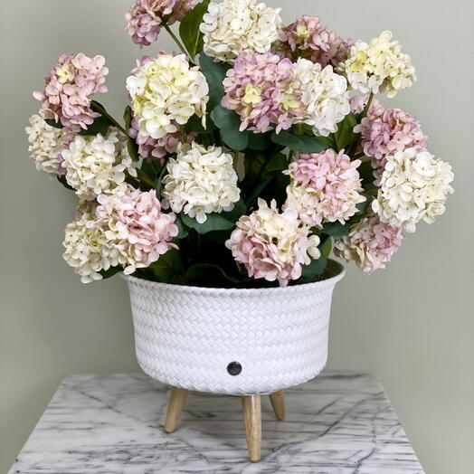 Ein hochwertiges kunstliches Hortensien-Arrangement in einem Rattantopf